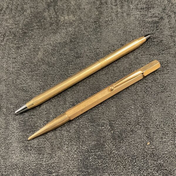 Vintage rolled gold pen and pencil set on a textured surface.