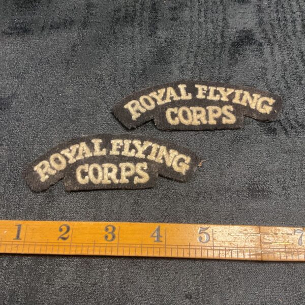 Pair of vintage Royal Flying Corps shoulder titles on dark cloth.