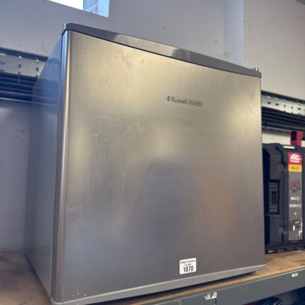 Silver Russell Hobbs mini fridge on a shelf.