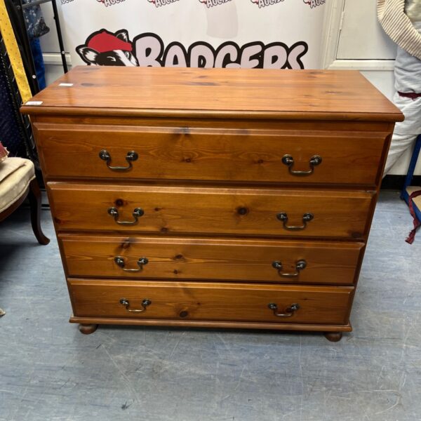 Rustic pine chest of drawers with four drawers and dark handles.