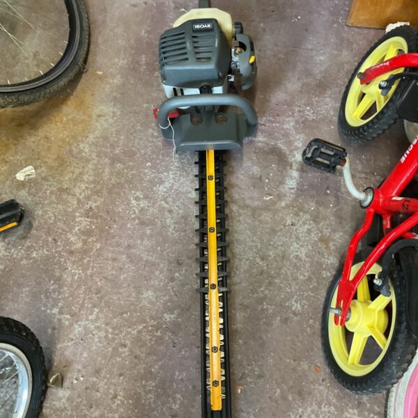 Close-up of a used Ryobi chainsaw with chain and handle visible.