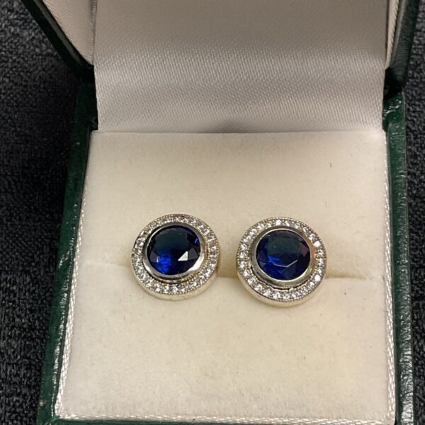Close-up of 925 silver sapphire and white stone stud earrings.