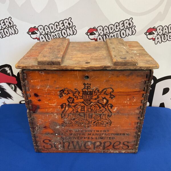 Antique Schweppes crate with faded advertising graphics.