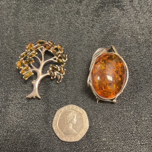 Vintage silver brooches with amber stones, floral and leaf designs.