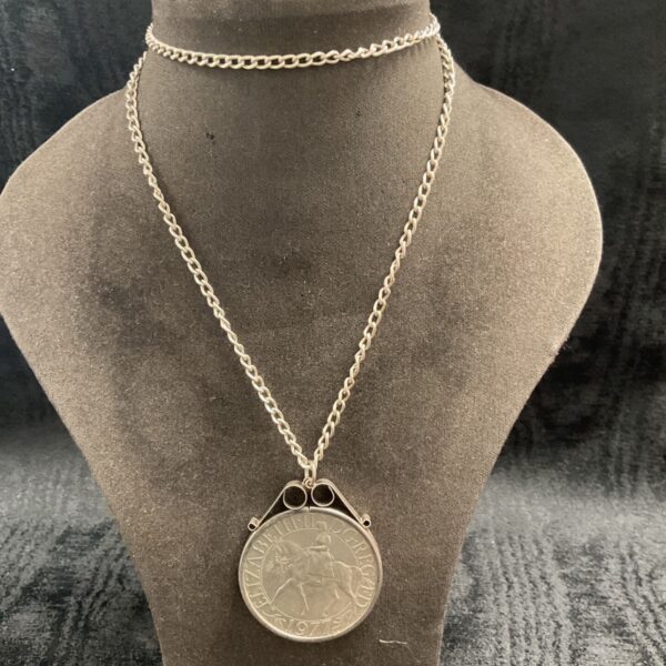 Close-up of silver coin necklace with commemorative coin pendant.