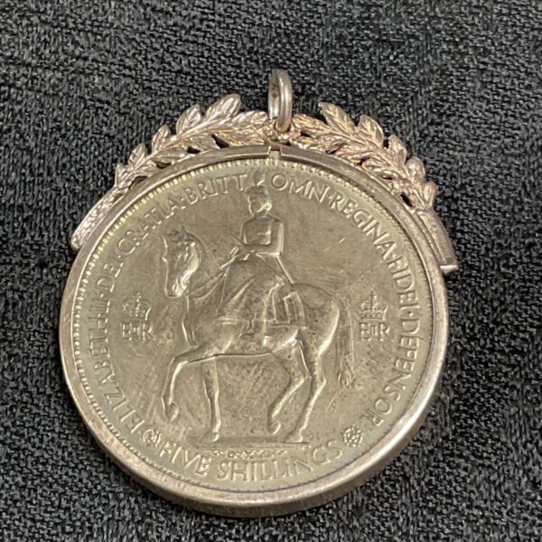 Antique silver commemorative pendant with equestrian coin detail.