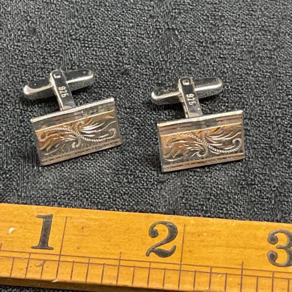 Intricate silver cufflinks with engraved floral design.