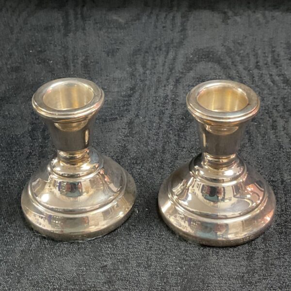 Pair of vintage silver filled candle sticks on a dark surface.