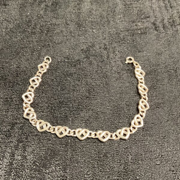 Close-up of a silver heart link bracelet, delicate and feminine.