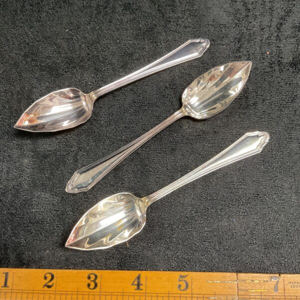 Vintage silver plate grapefruit spoons set on a neutral background.