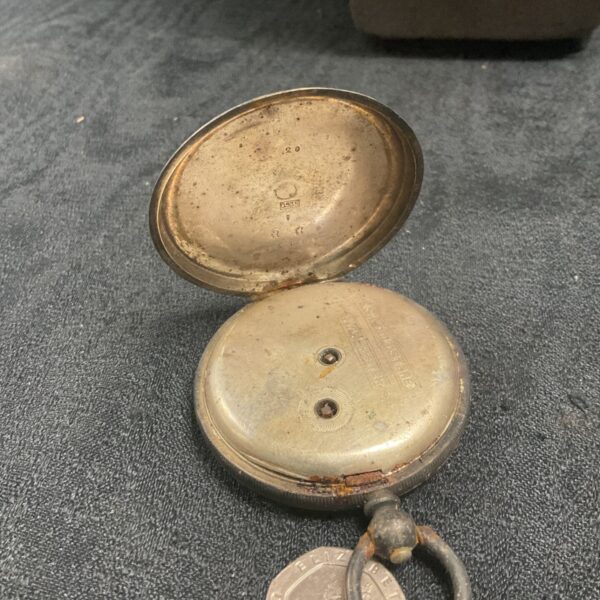 Open silver pocket watch case showing internal mechanism.