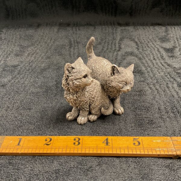 Silver resin cats figure with ruler for scale.