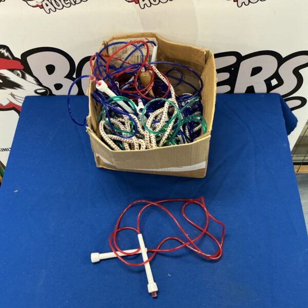 Mixed lot of colourful skipping ropes in a cardboard box.