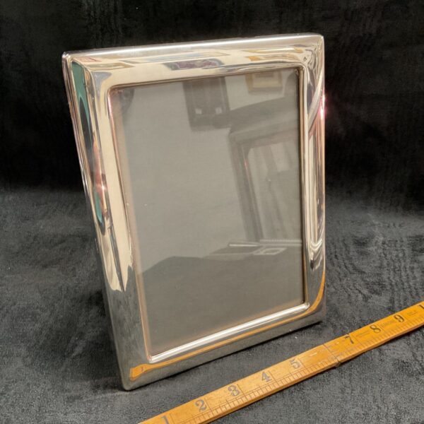Hallmarked sterling silver photo frame with a reflective surface.
