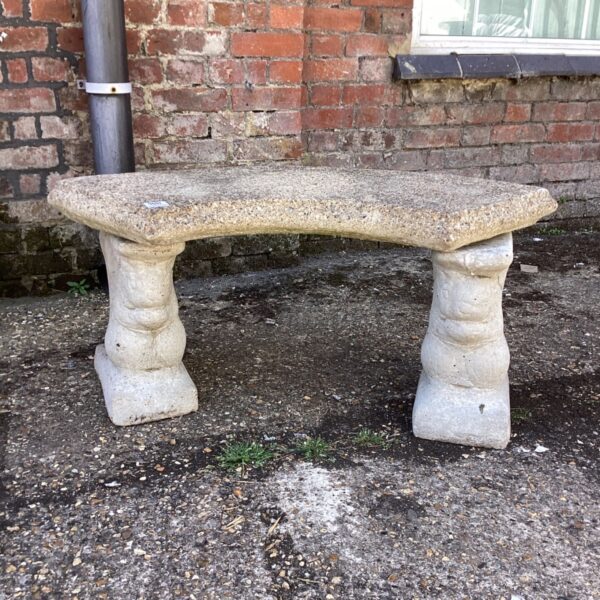 Weathered stone garden bench in a garden setting.