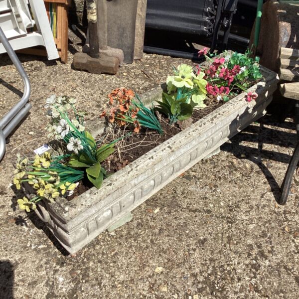 Stone effect garden planter with colourful floral display outdoors.