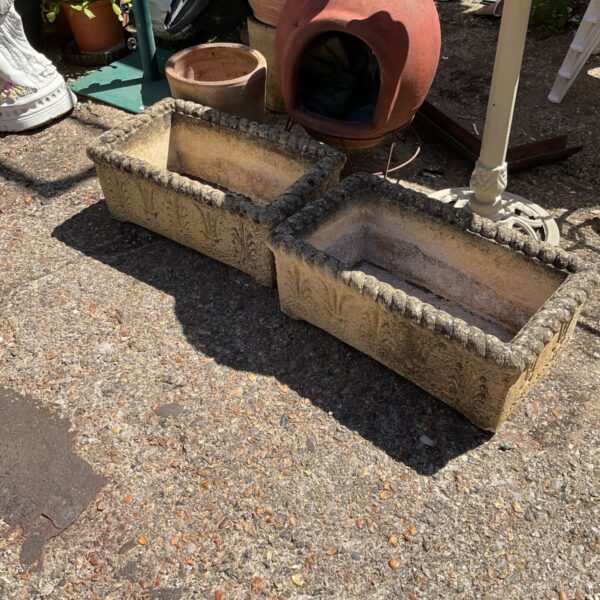 Pair of weathered stone effect garden planters in a garden setting.