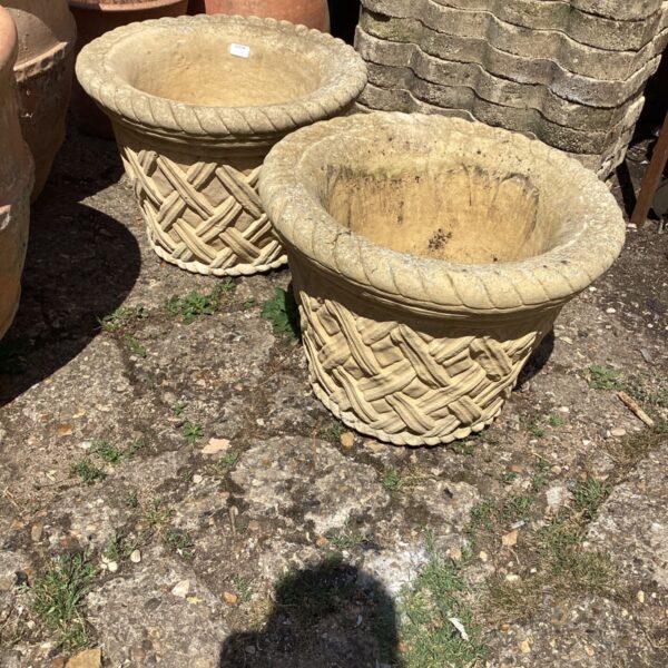 Pair of weathered stone lattice garden planters for outdoor use.