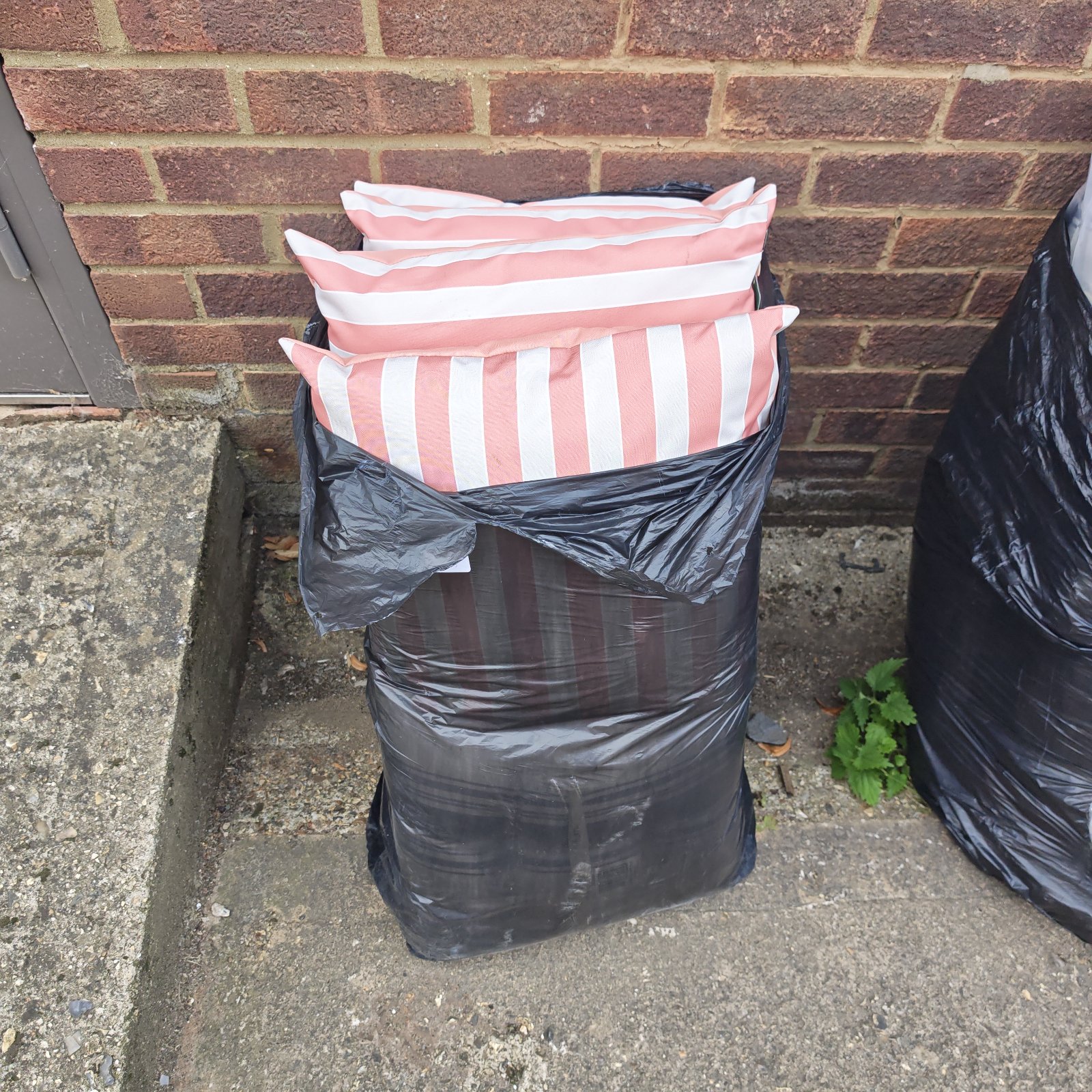 Pink and white striped garden seat cushions in a black bag.