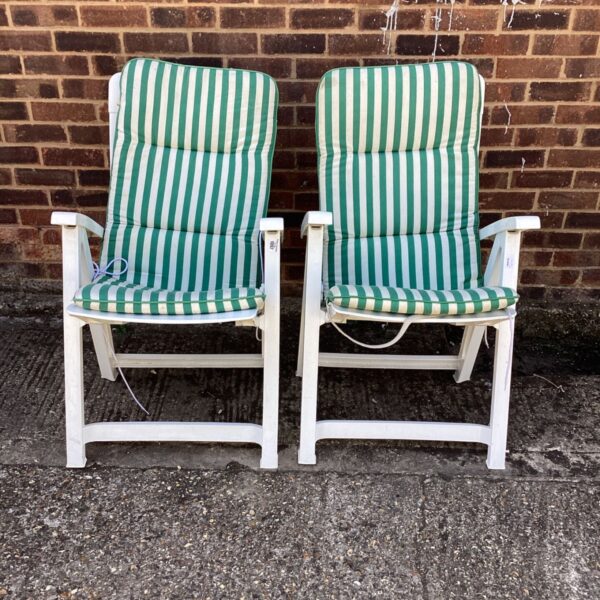 Two striped sun loungers in a garden setting.