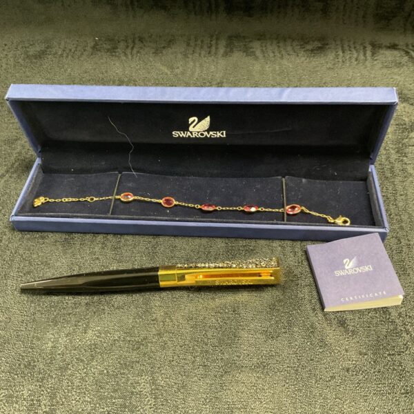 Swarovski red crystal bracelet and pen set displayed on a certificate.