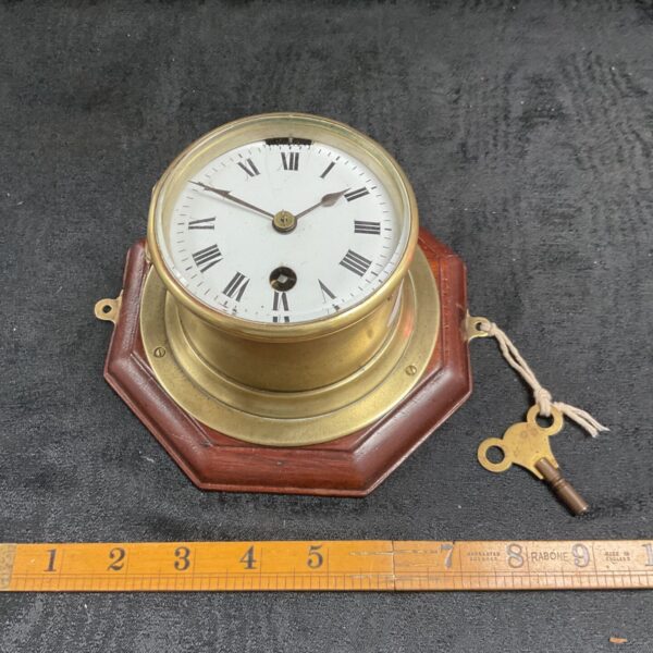 Antique Swiss brass bulkhead clock with key, ideal for collectors.