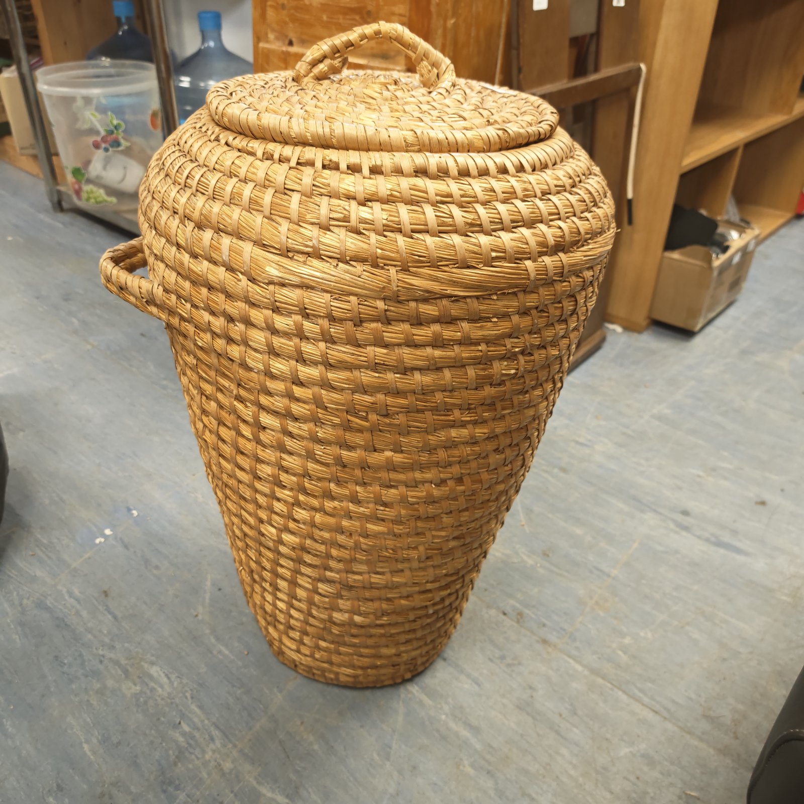 Tall woven wicker laundry basket with lid for rustic storage.