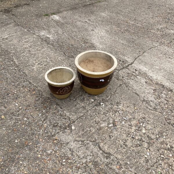 Two weathered terracotta garden planters displayed outdoors.