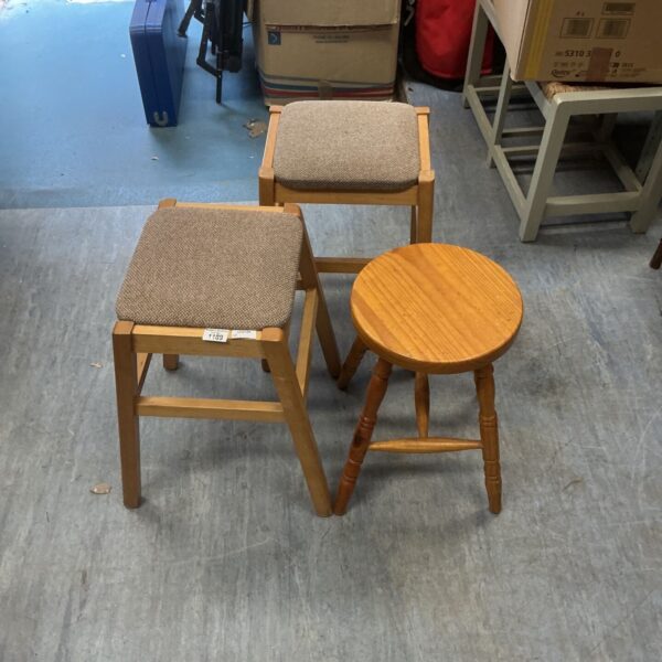 Three rustic pine stools with upholstered seats.