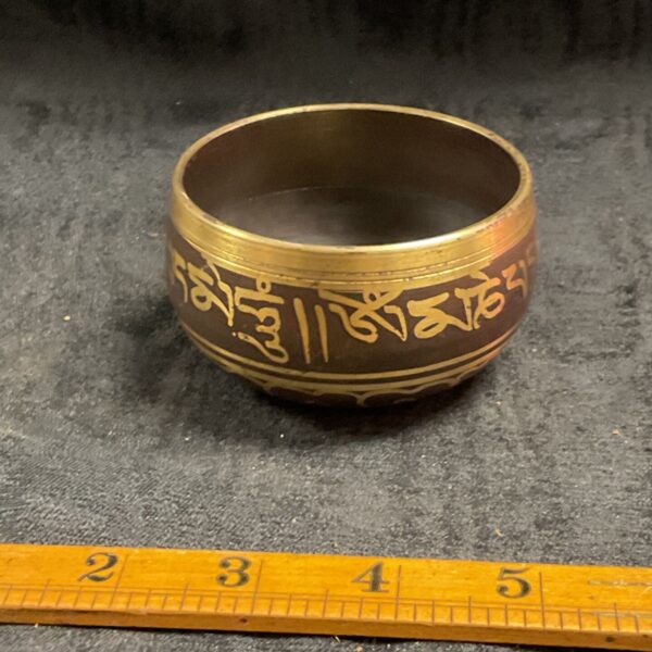 Antique Tibetan singing bowl with mantra script detail.