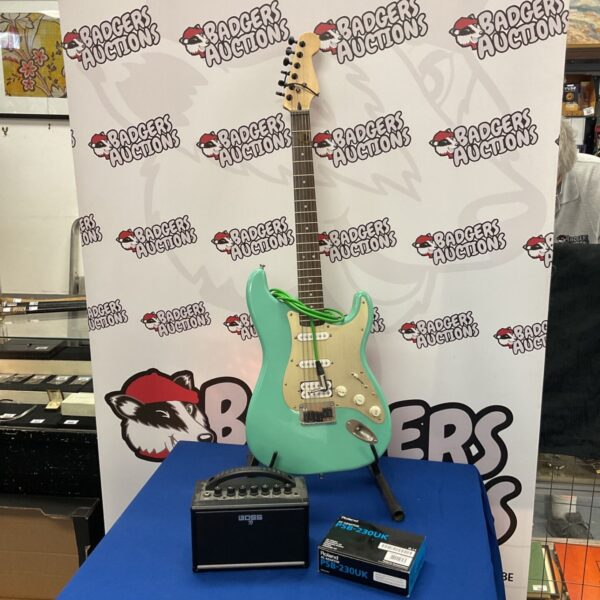 Turquoise electric guitar with Boss practice amplifier for auction.