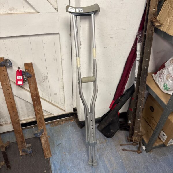 Silver underarm crutches with black grips, a mobility aid.