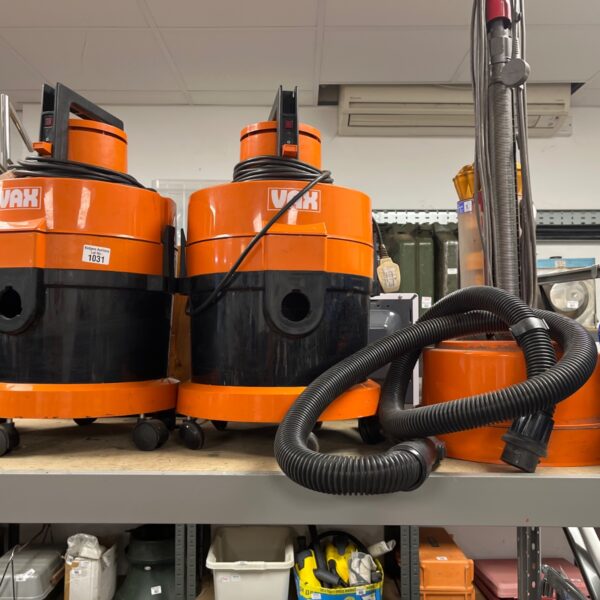 Pair of orange Vax hoovers with long hoses for floor cleaning.