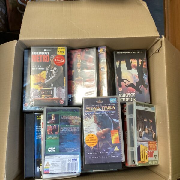 Box filled with a vintage VHS tape collection, including Star Trek.