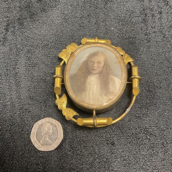 Victorian morning brooch with a portrait and a coin for scale.