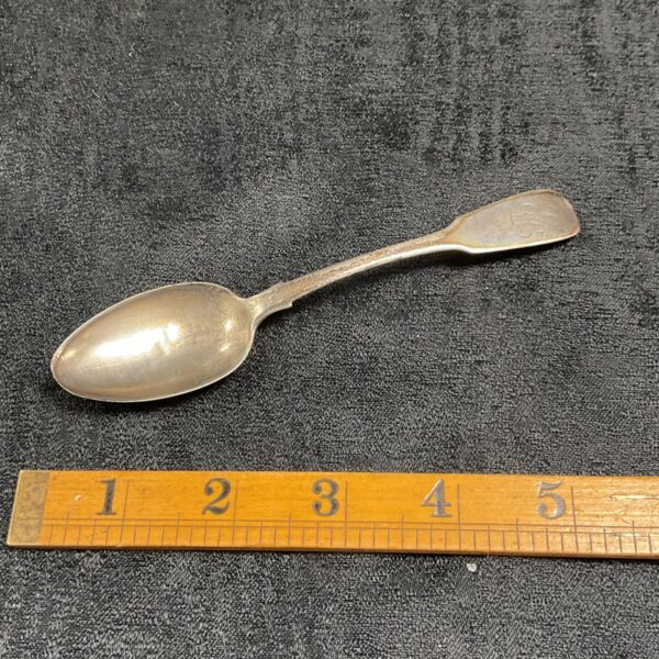 Antique Victorian silver teaspoon with ruler for scale.