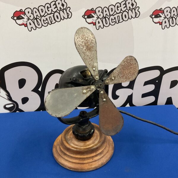 Vintage 1930s desk fan with metal blades and a circular base.