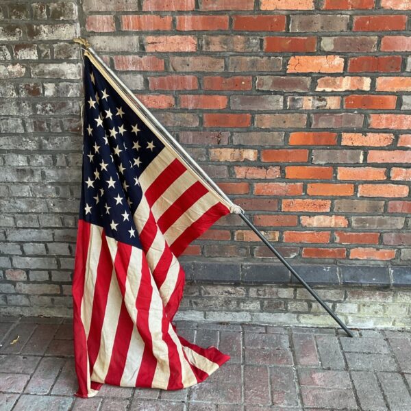 Large vintage American flag on a pole, showing wear.