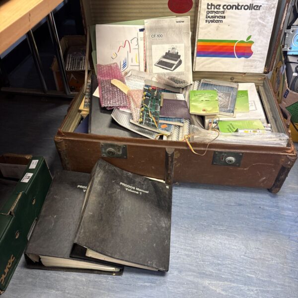 Vintage Apple accessories and manuals inside a weathered trunk.