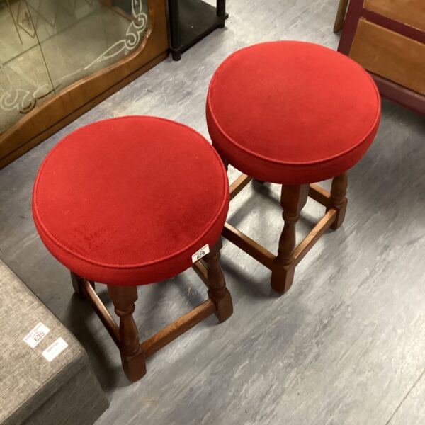 Pair of vintage wooden bar stools with red fabric seats.