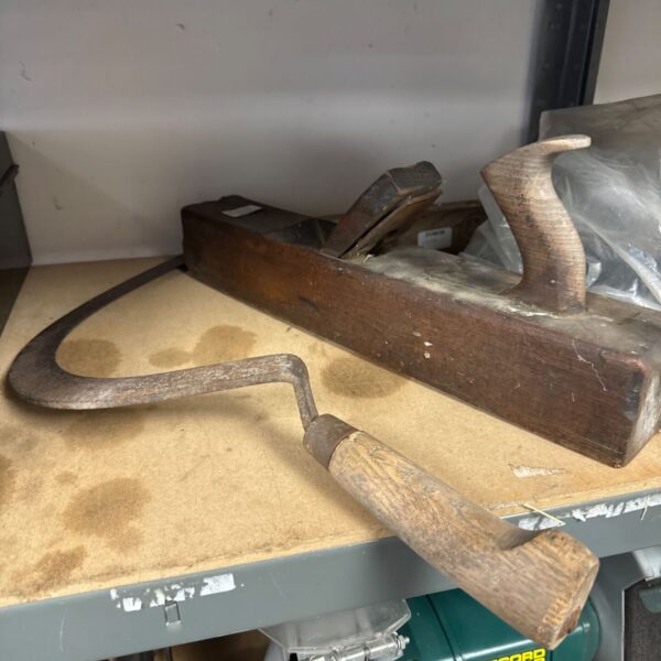 Vintage block wood plane with scythe blade for woodworking.