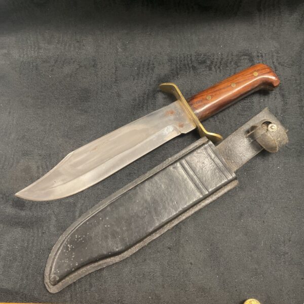 Vintage Bowie knife with leather sheath, a collectible hunting tool.