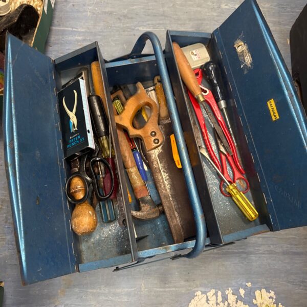 Vintage cantilever toolbox filled with antique tools for storage.