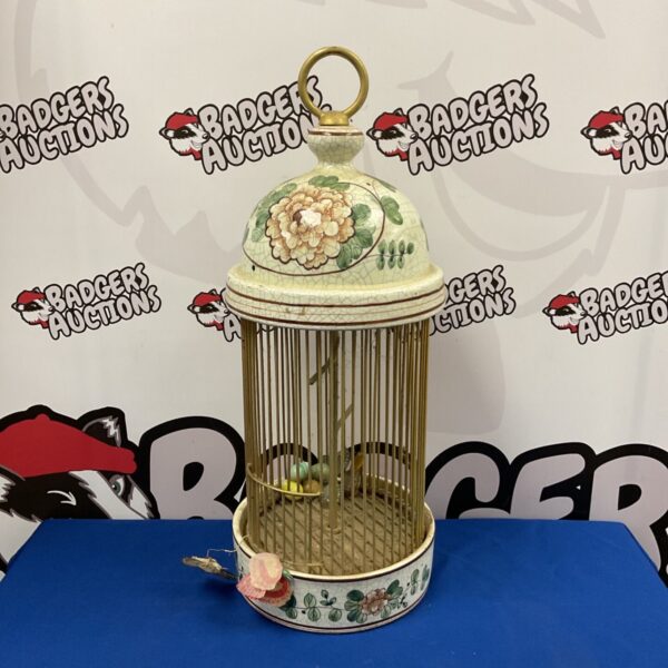 Vintage ceramic bird cage with floral details and gilded bars.