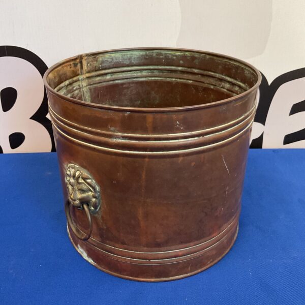Vintage copper bin with ornate lion head handles.