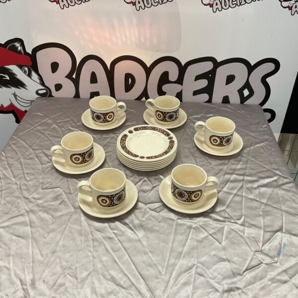 Vintage earthenware tea set with cups and saucers on a white surface.