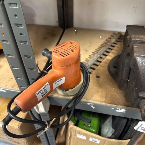 Vintage electric hedge trimmer with a black handle and worn plastic casing.
