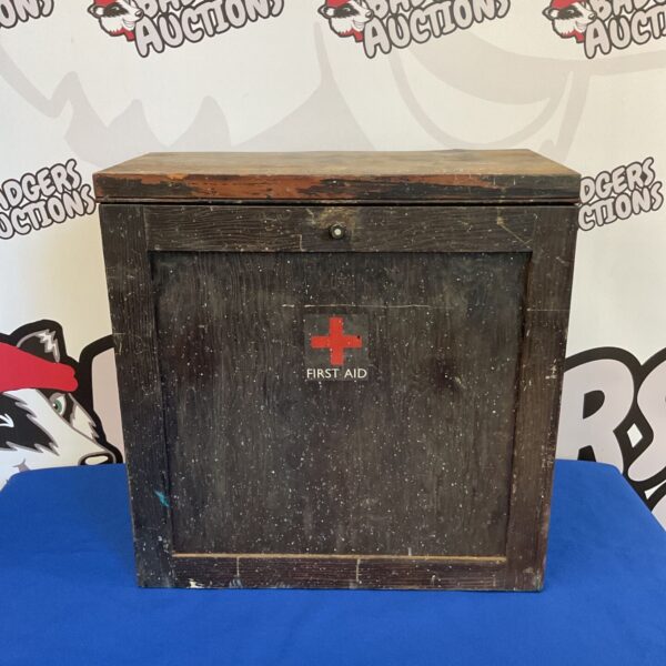 Vintage wooden first aid cabinet with red cross.