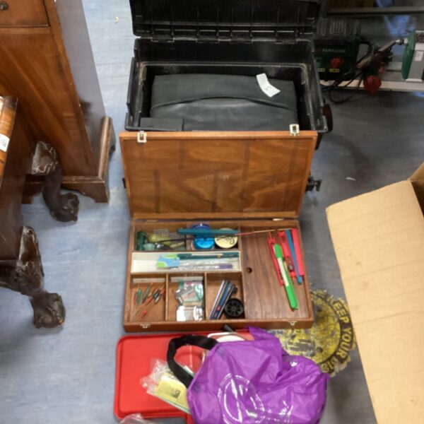Open vintage wooden fishing tackle box with fishing gear inside.