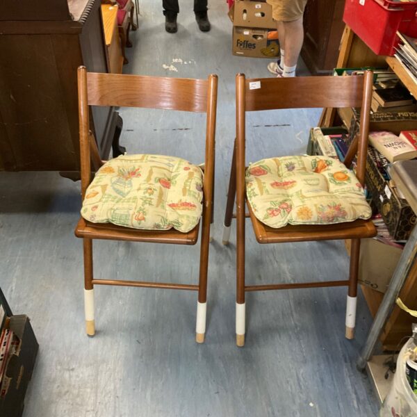 Vintage folding chairs with floral patterned seats and white legs.